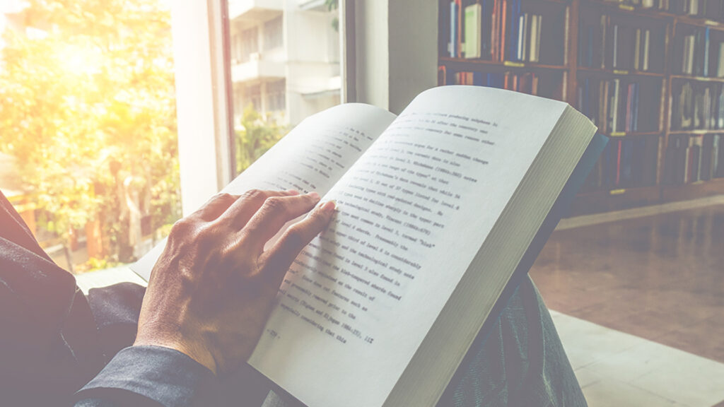 Närbild på en öppen bok och en hand